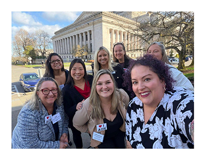 Group of eight women smiling for a selfie in front of the Washington State Capitol building at the WSCAI Olympia Day Legislative Summit